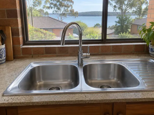 Kitchen sink with chrome mixer tap beside a tiled splashback and window in Bolton Point